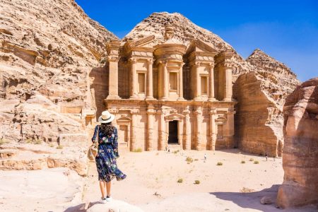 Asian young woman in colorful dress and hat enjoying at The Monastery, Petra's largest monument, UNESCO World Heritage Site, Jordan.